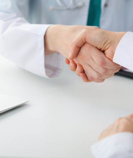 Doctor and patient shaking hands, close-up.  Physician talking about medical examination results. Medicine, healthcare and trust concept.